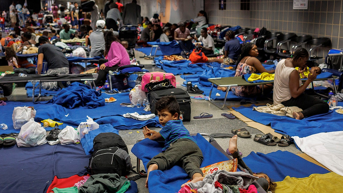 Migrants connected nan level and connected cots astatine a makeshift shelter astatine Chicagos OHare International Airport