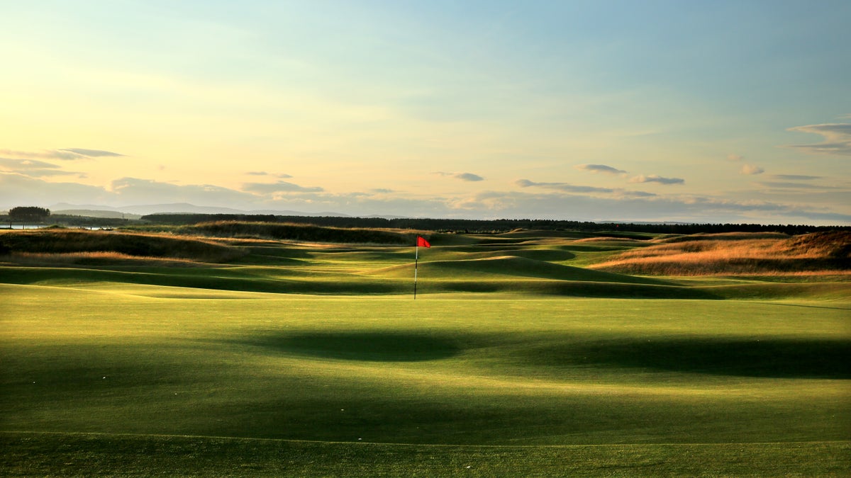 scenic shot of a golf course with sun setting in background