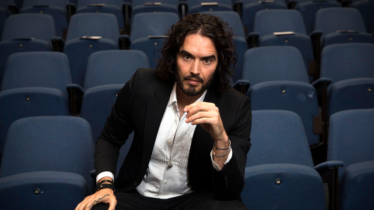 Russell Brand sitting in a chair