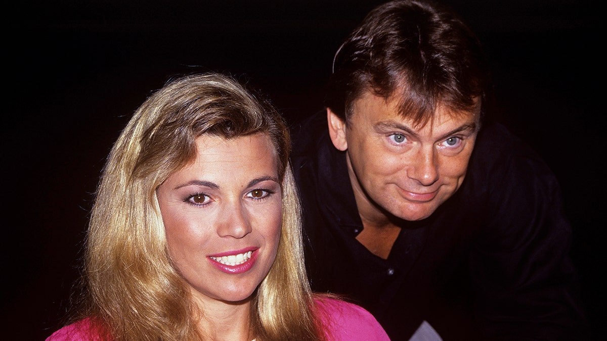 Pat Sajak leaning over Vanna White in 1990s era photo