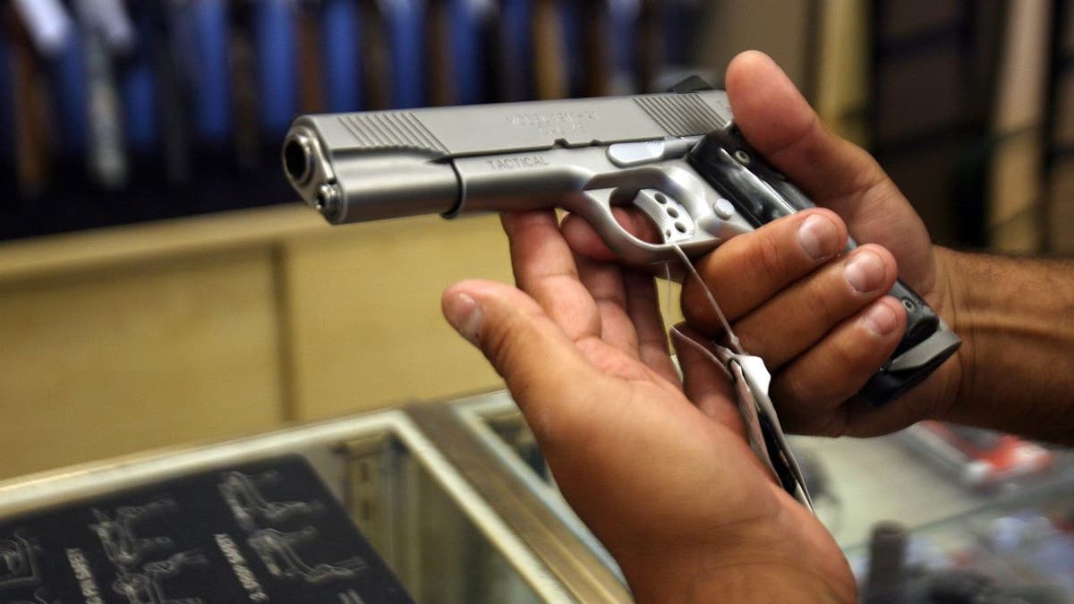 Hand holding gun in gun store