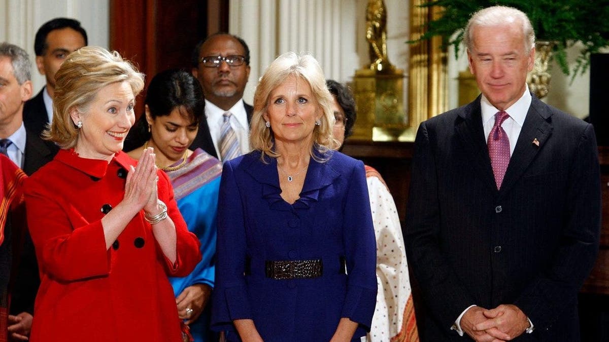Secretary of State Hillary Clinton (L) bows to members of the Indian delegation
