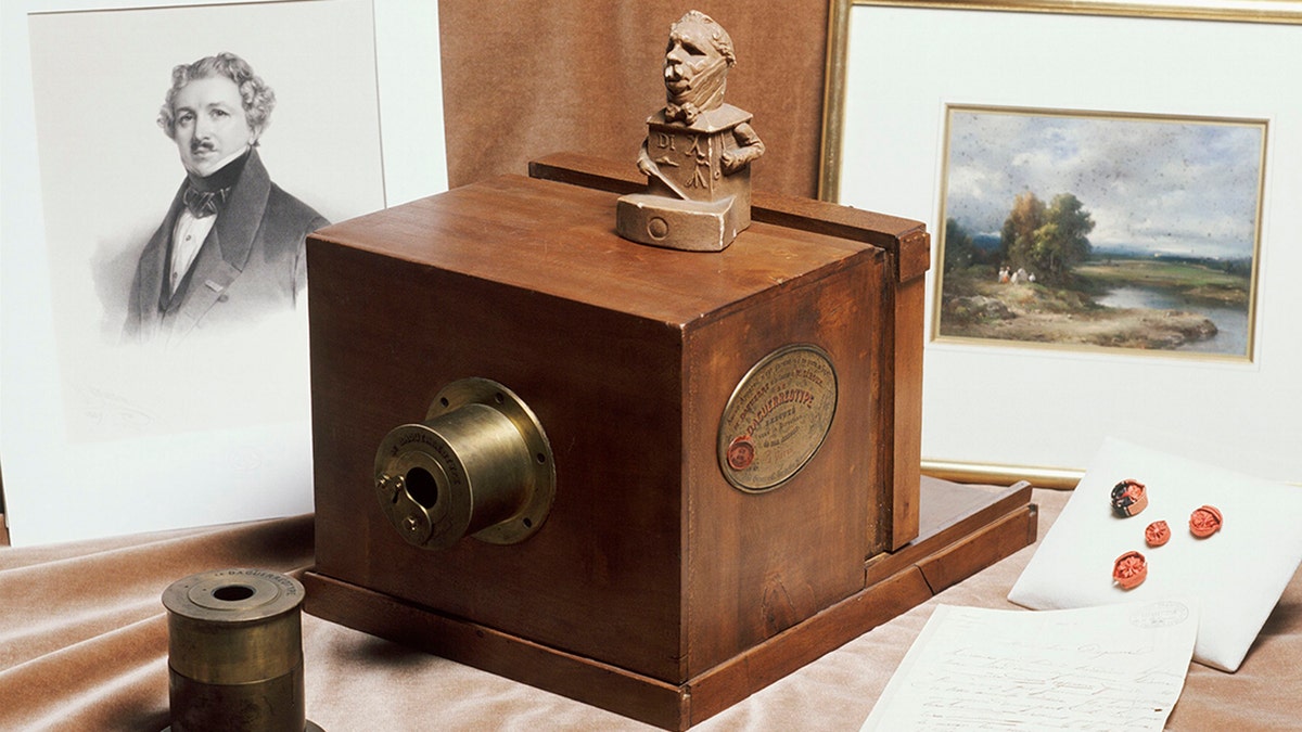 A daguerreotype camera made by Alphonse Giroux in Paris in 1839 and a portrait of Louis Jacques Mandé Daguerre are exhibited by the French Company of Photography. Shot taken around 1980.