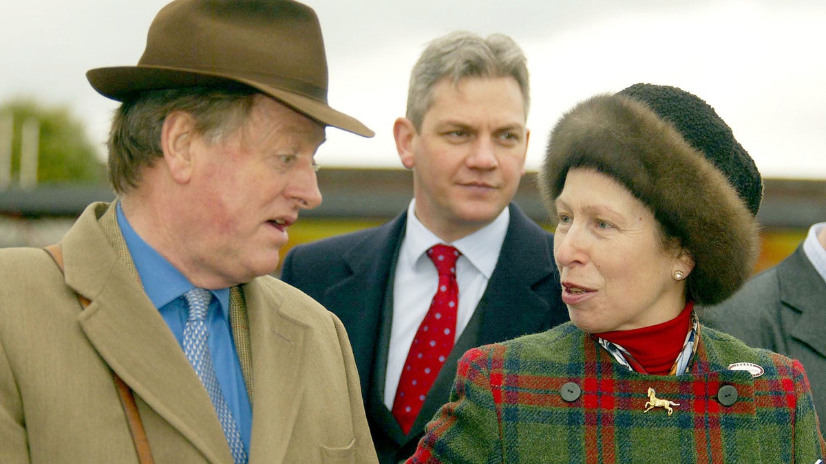Princess Anne in a plaid coat talking with Andrew Parker Bowles in a trench coat and blue shirt