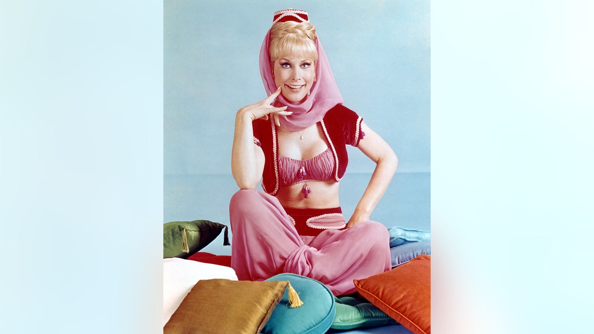 Barbara Eden, US actress, in costume sitting on a multi-coloured pile of cushions