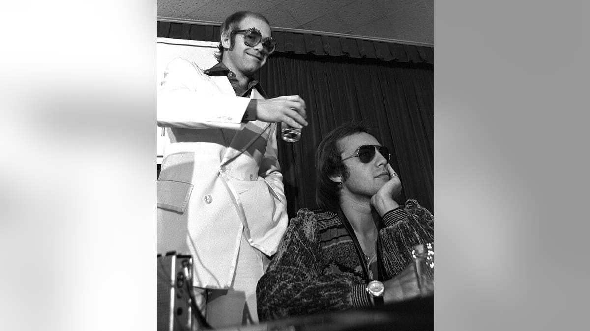 Elton John jokes about pouring water on Bernie Taupin's head during press conference