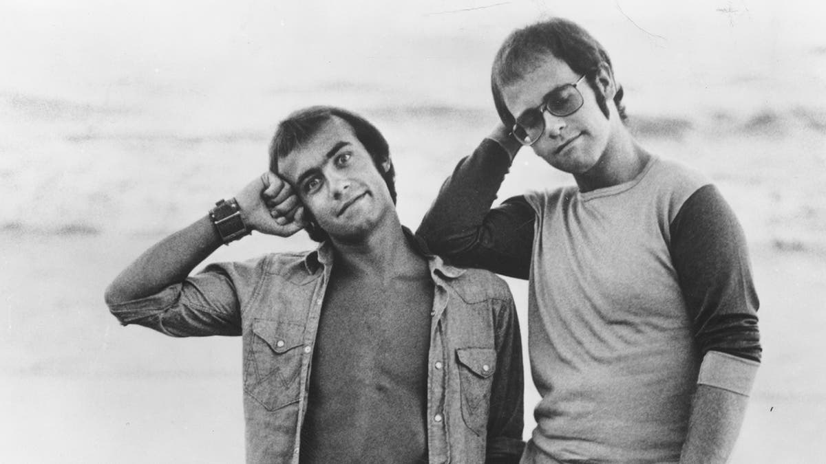 Elton John and Bernie Taupin pose on the beach