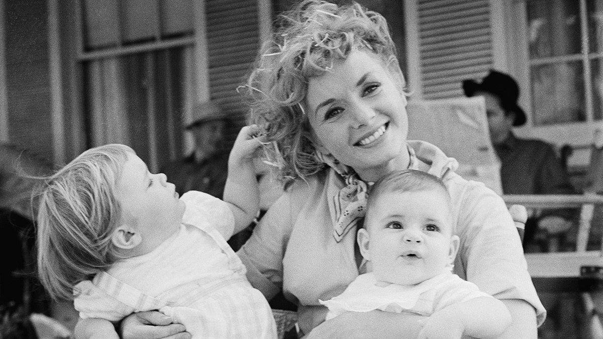 Debbie Reynolds smiling while holding her two children