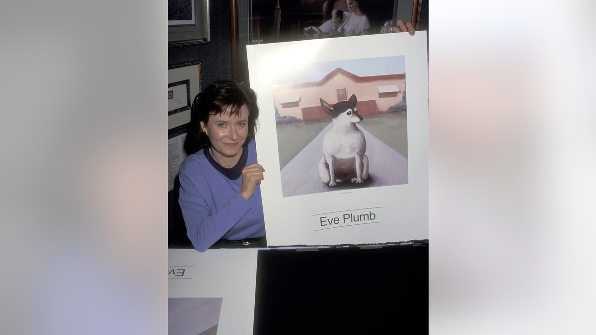 Eve Plumb wearing a purple sweater and holding a dog print