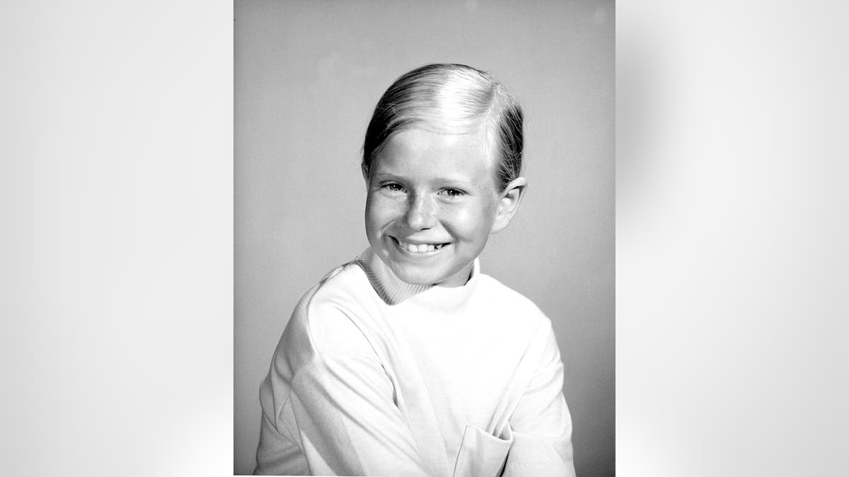 A young Eve Plumb wearing a white turtleneck sweater