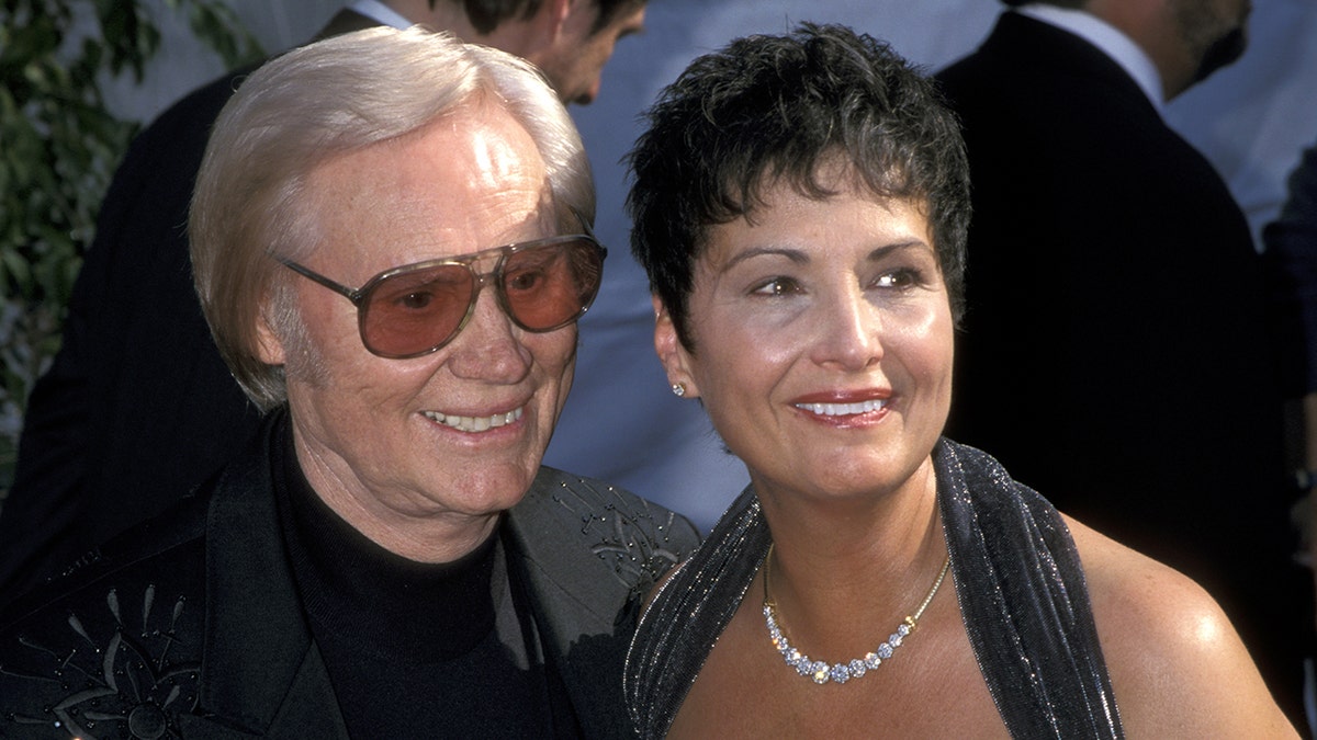 A close-up of George Jones wearing black and Nancy Jones wearing a matching halter dress