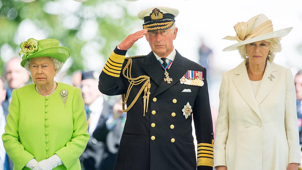 Queen Elizabeth wearing a lime green dress, Prince Charles in a military suit and Camilla wearing a cream dress