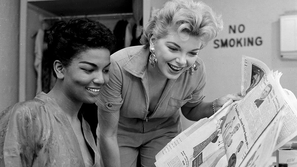 Loray White and Barbara Nichols smiling and looking at a newspaper together