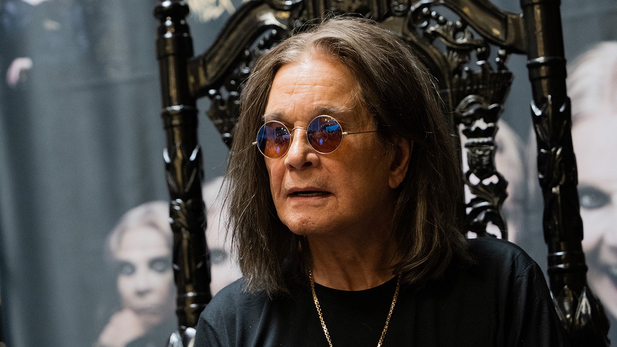 A close-up of Ozzy Osbourne sitting on a black chair