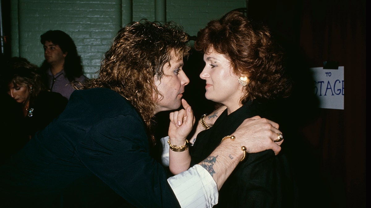 Ozzy Osbourne staring at his wife Sharon as she touches his face