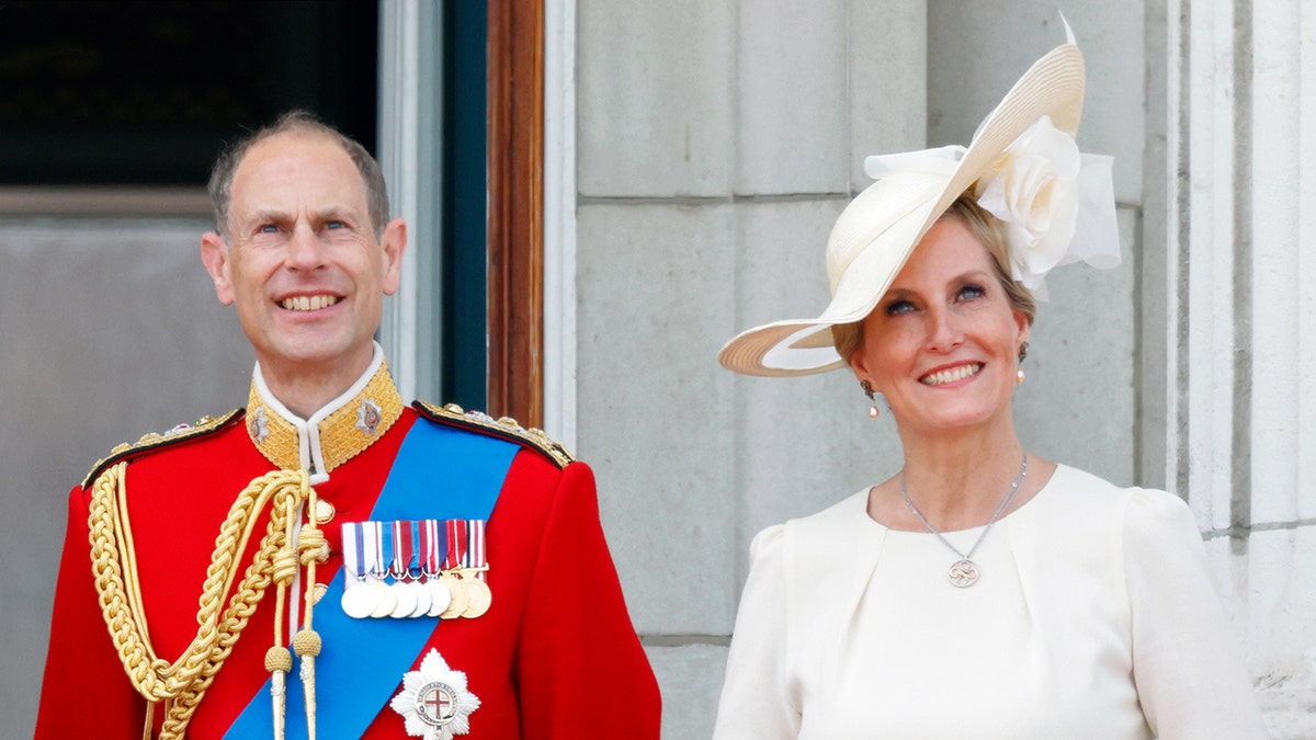 A close-up of the Duke and Duchess of Edinburgh wearing royal formal wear while standing on the balcony of Buckingham Palace
