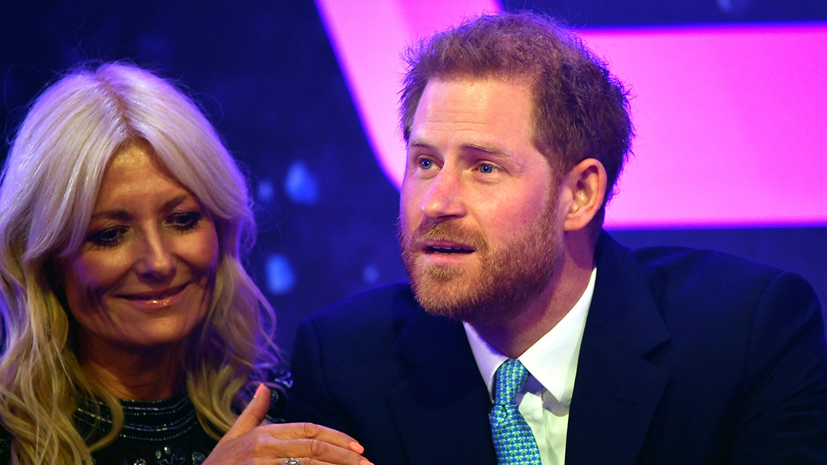 A close-up of Prince Harry getting visibly emotional as a woman holds his arm