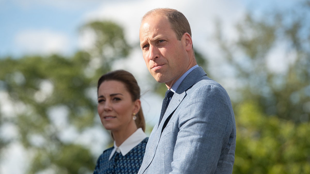 Prince William in a grey suit next to Kate Middleton in a polka dot dress