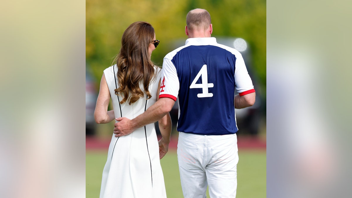 Kate Middleton is wearing a white dress and Prince William is wearing a polo uniform with their backs turned