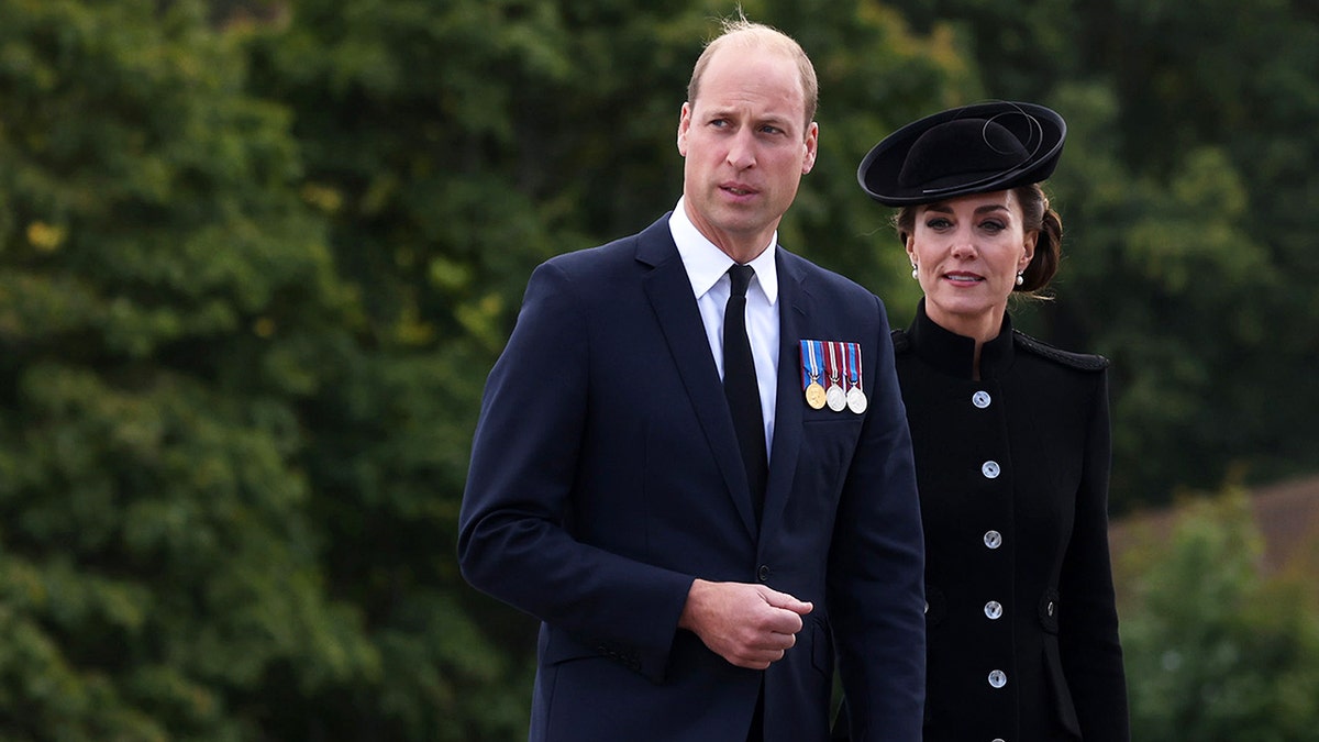 Prince William and Kate Middleton wearing dark clothing outdoors