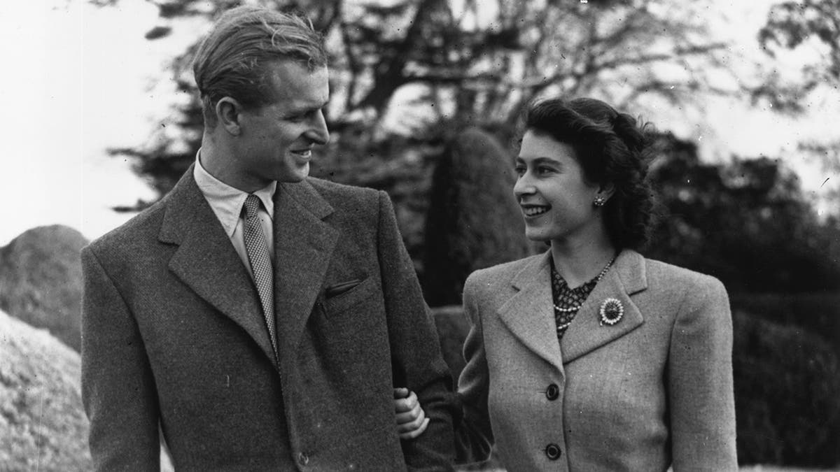 A young Prince Philip and Princess Elizabeth admiring each other outdoors