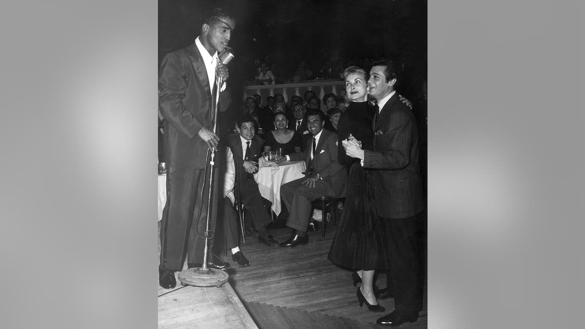 Sammy Davis Jr. performing in front of Tony Curtis and Janet Leigh