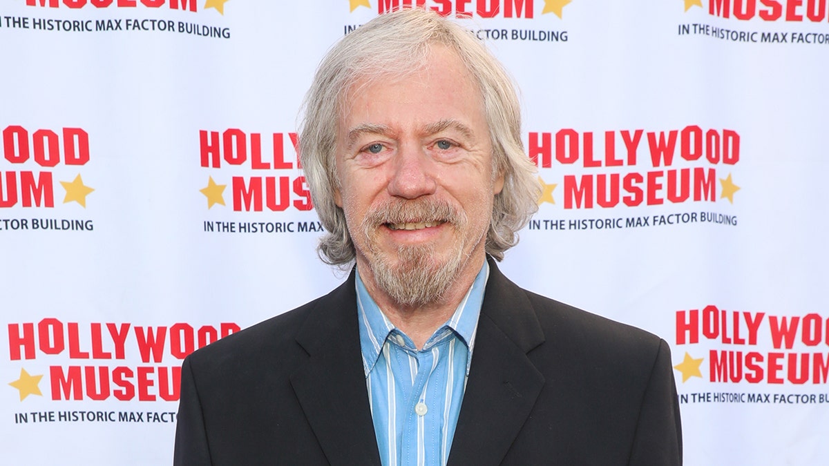 A close-up of Stanley Livingston in a blue and white striped shirt and a black blazer