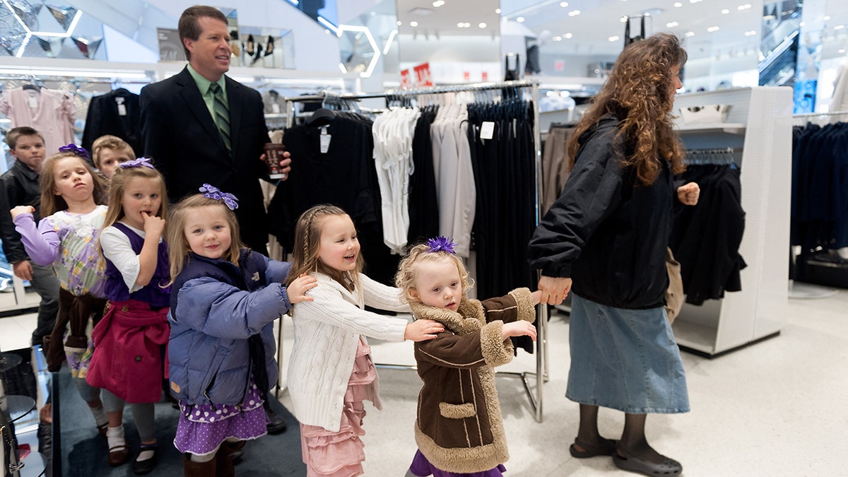 The Duggar family walking in a straight line at a clothing store