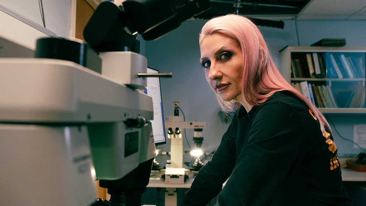 Alina Burroughs looking away from a microscope