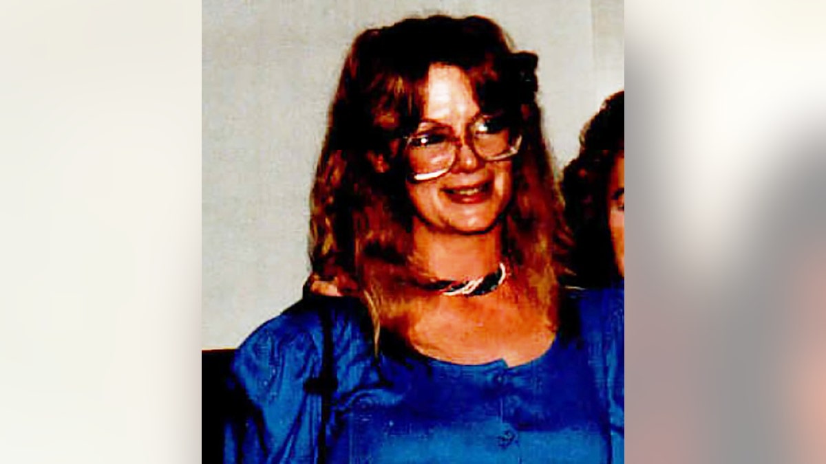 Margie Coffey wearing a bright blue dress and glasses