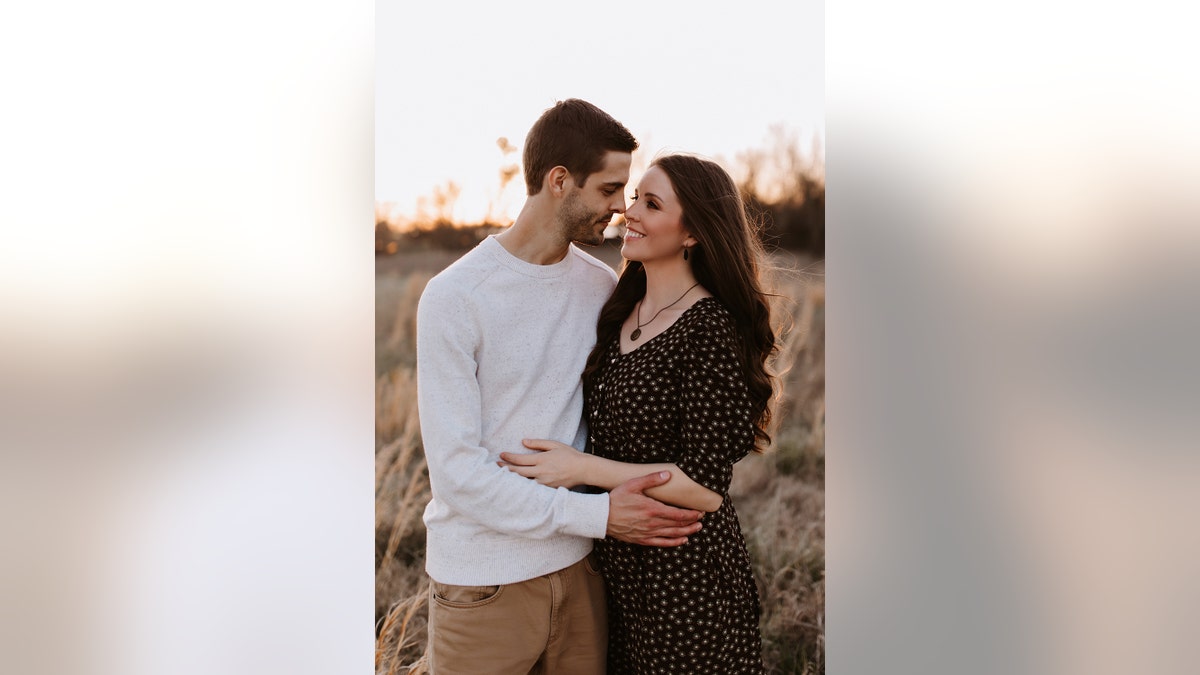 Derick Dillard wearing a white sweater embracing his wife Jill Duggar in a black polka dot dress