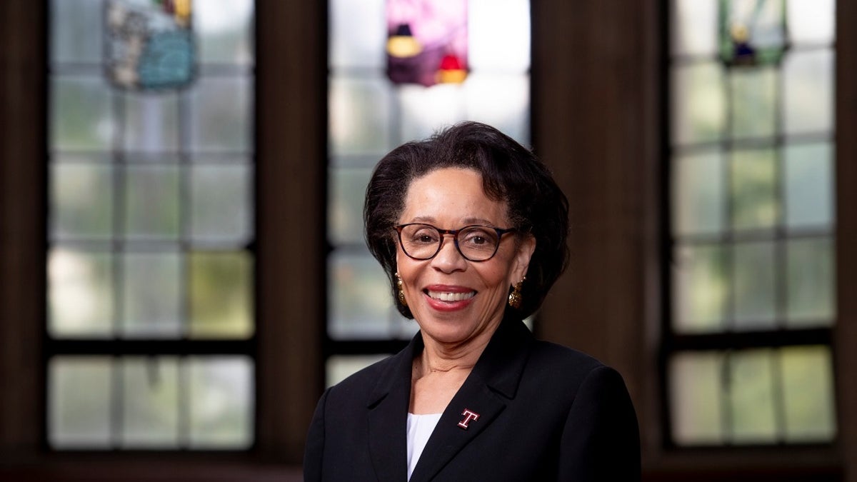 Waarnemend president van Temple University, JoAnne Epps, poseert alleen voor glas-in-loodramen en donkere houten muren