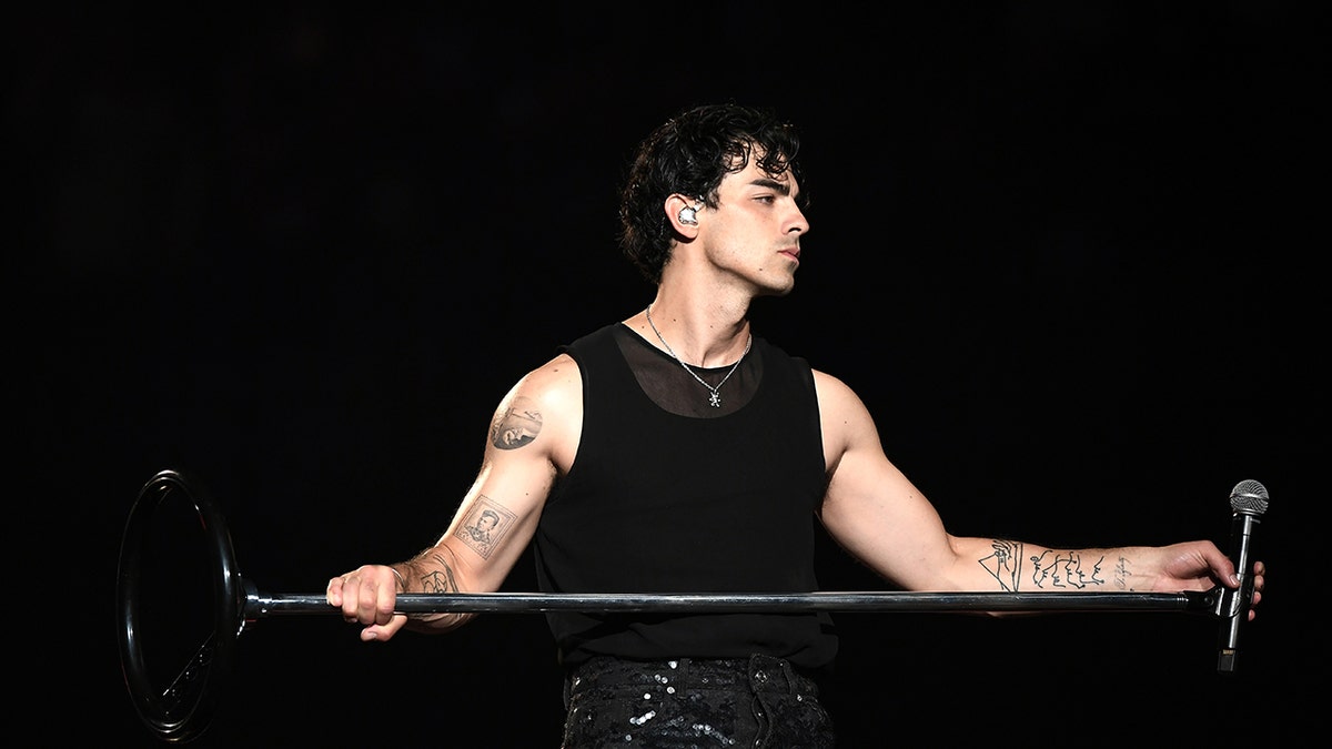 Joe Jonas holds the microphone stand on stage