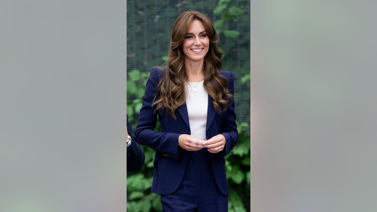 Kate Middleton walking in navy blue pantsuit with injured hand