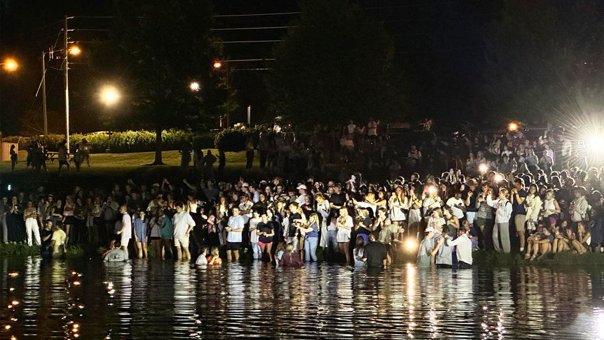 Hundreds of students gathered lakeside at night for baptisms