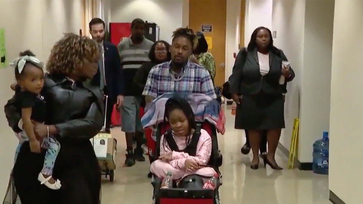 A group of people walking through a courtroom hallway.