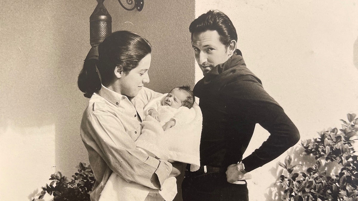 Prince Michael of Greece wearing all black as Marina Karella wears all white while holding their baby