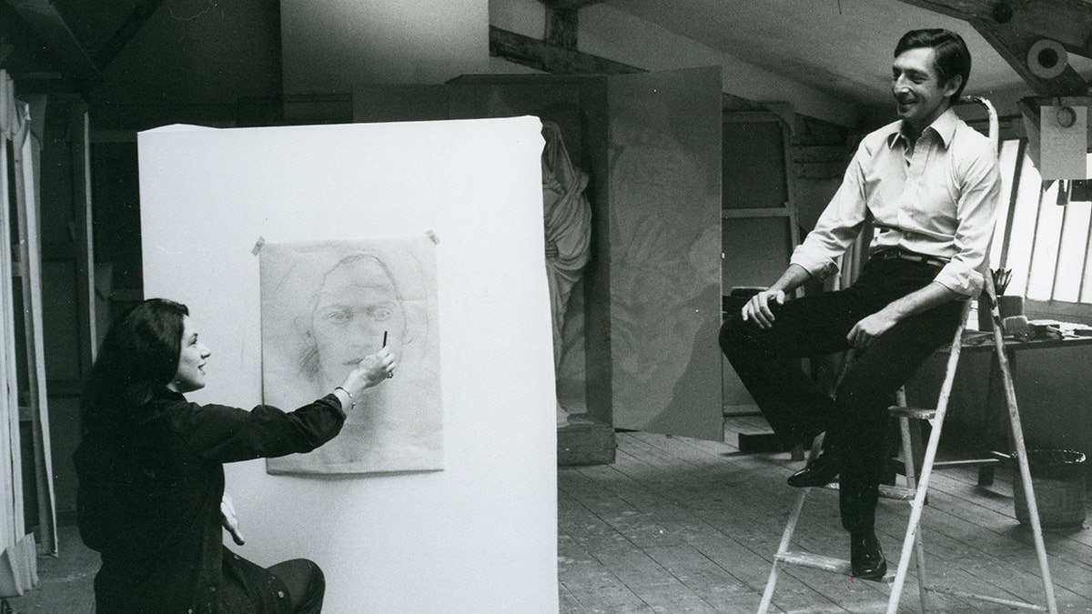 Prince Michael of Greece in formal wear posing for a painting being made by his wife