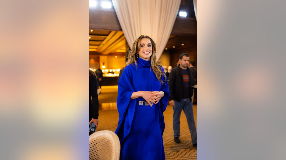 Queen Rania of Jordan wearing a bold blue long sleeved dress