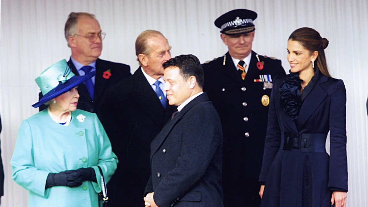 The King and Queen of Jordan in dark suits chatting wiht Queen Elizabeth II in a teal dress