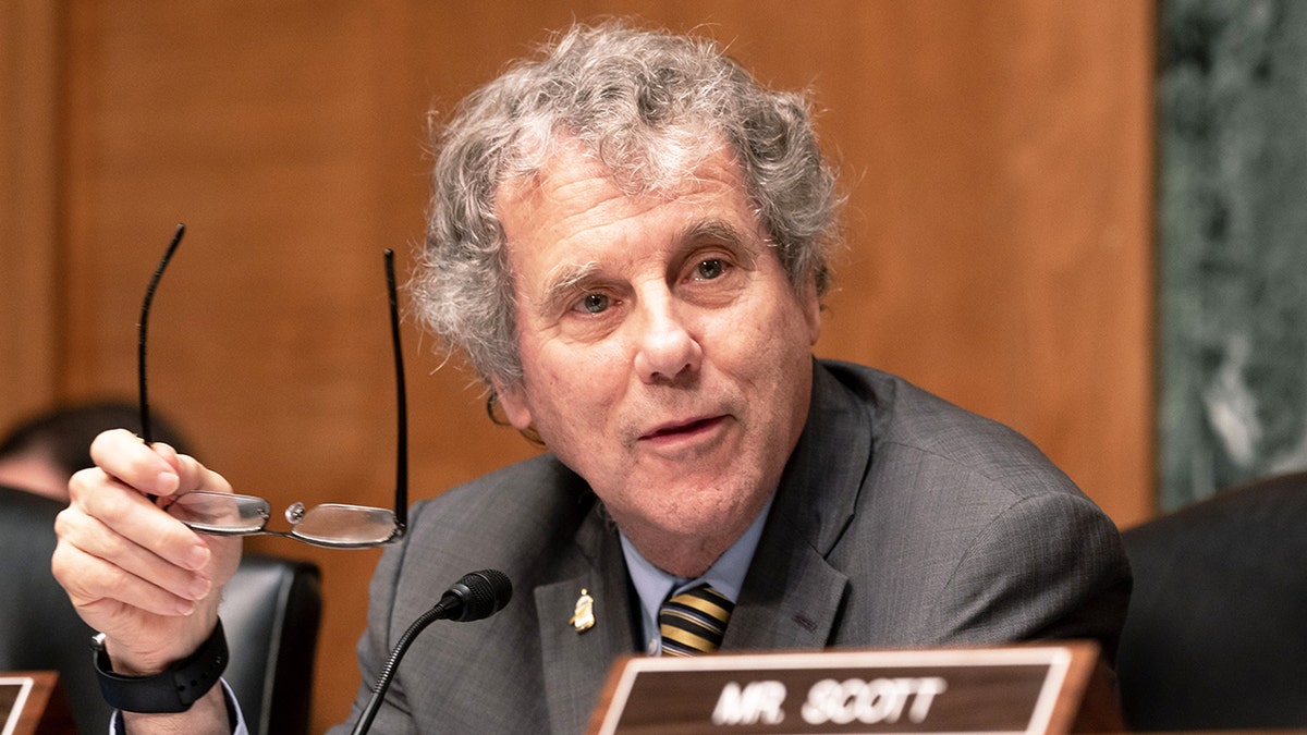 Sherrod Brown holding glasses during hearing