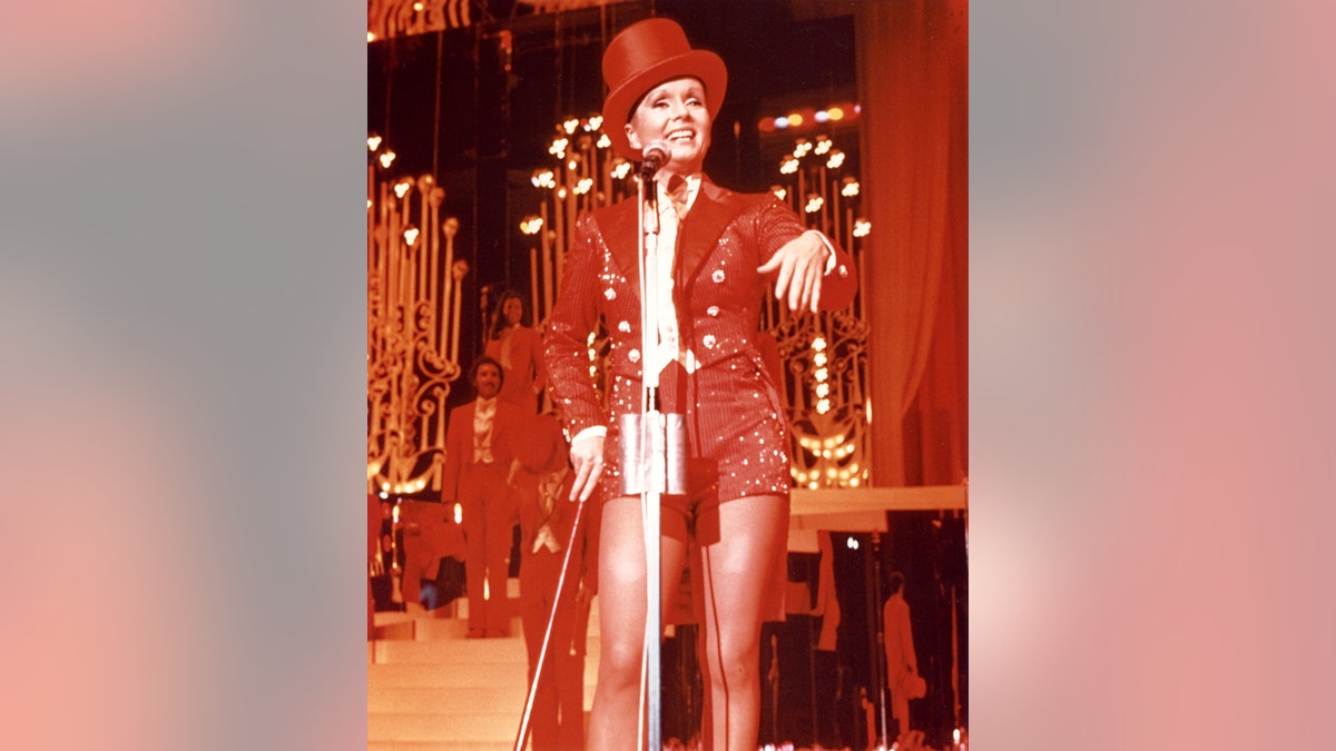 Debbie Reynolds wearing a red costume on stage