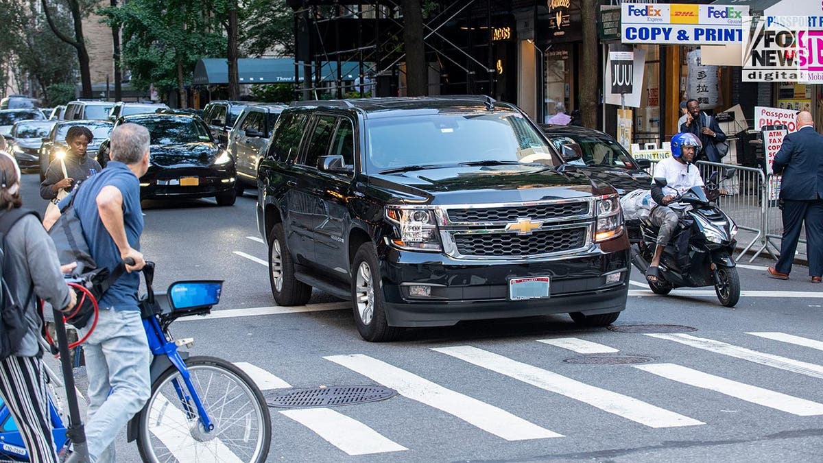 A car moves through the intersection as pedestrians wait on both sides