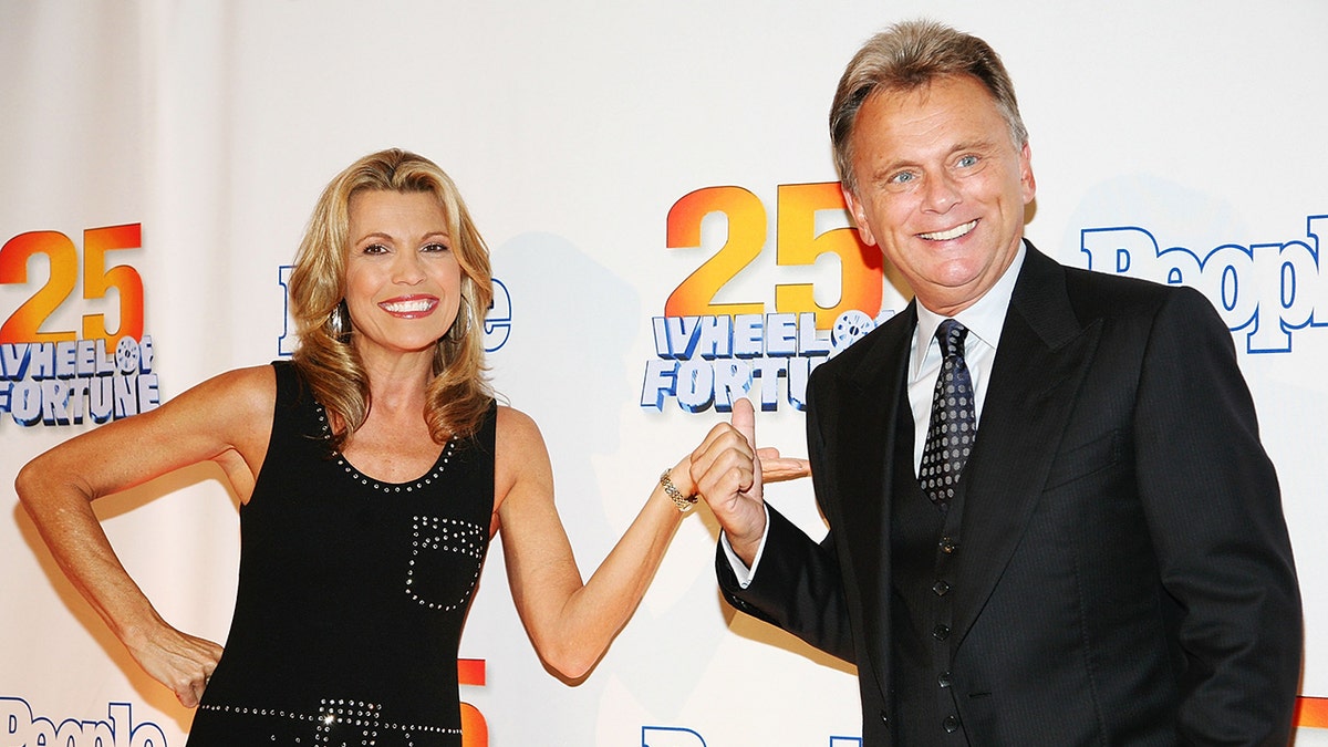 Vanna White and Pat Sajak gesturing at each other