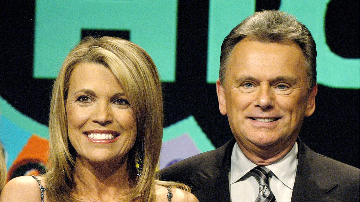 Close up of Vanna White and Pat Sajak smiling on set