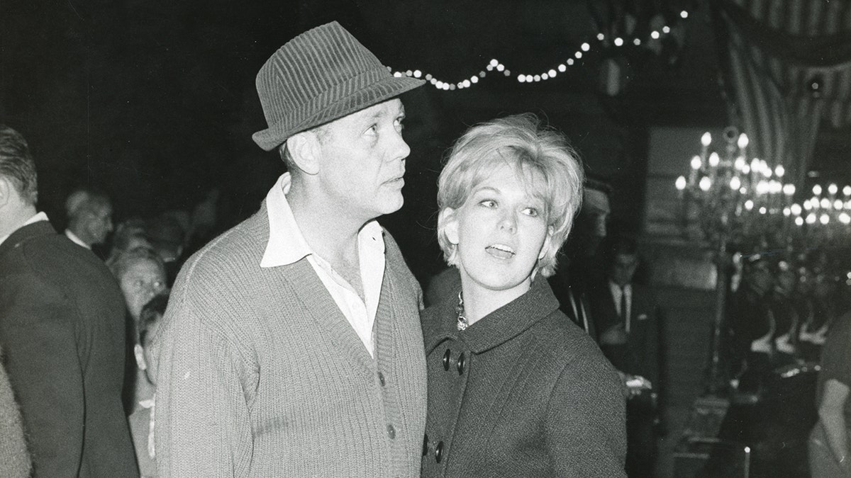 Richard Quine and Kim Novak wearing dark suits and looking away from the camera
