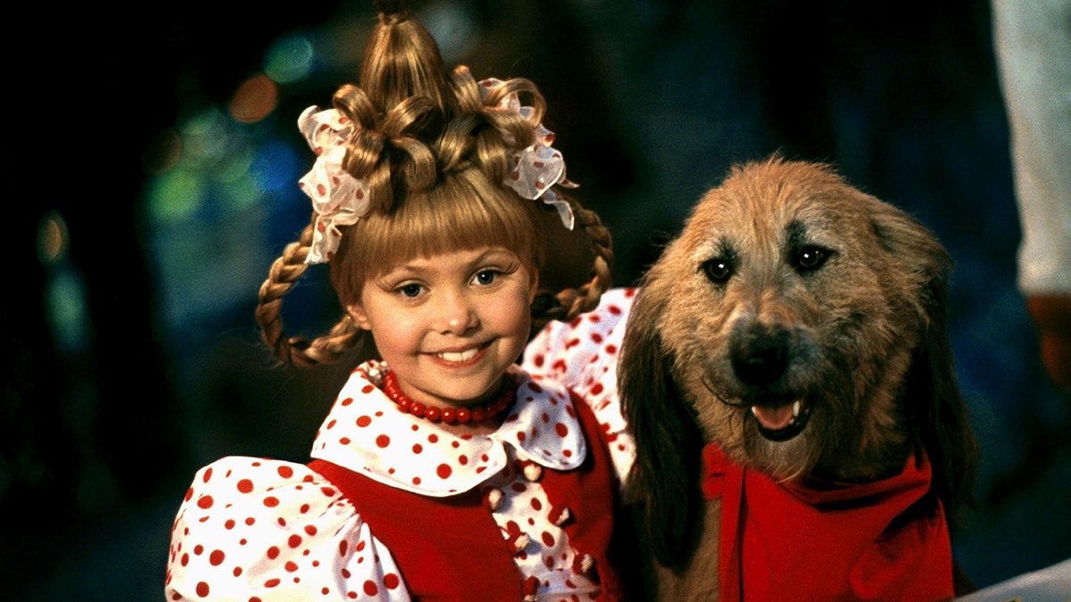 Taylor Momsen as Cindy Lou Who from "How The Grinch Stole Christmas" in a polka dot shirt and matching bows posing next to a dog