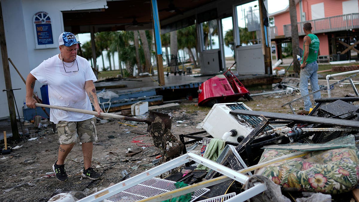 Employee Lisa Bell dumps out a shovel full of mud in Horseshoe Beach, Florida, on Aug. 31, 2023, one day after the passage of Hurricane Idalia.