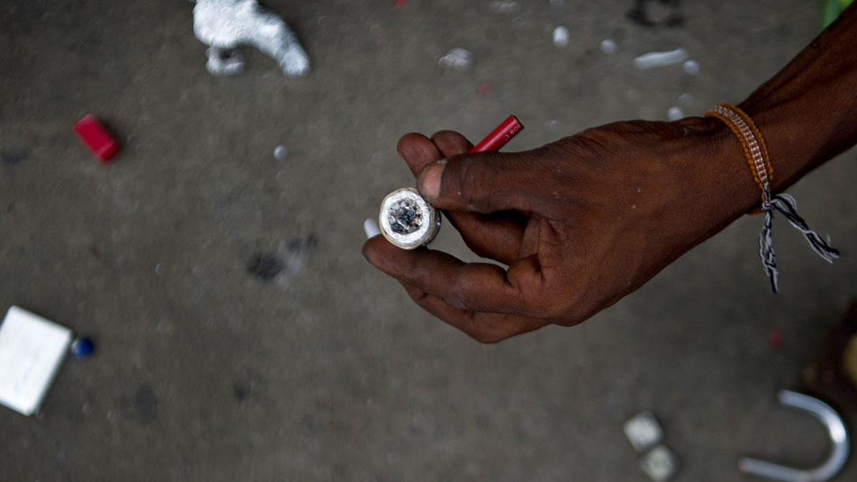 A drug addict holds a crack pipe