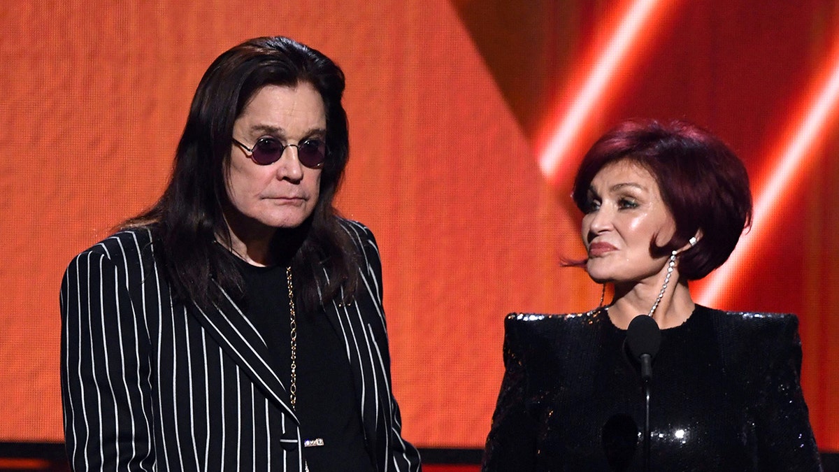 Ozzy Osbourne wearing a black and white striped blazer next to Sharon wearing a black dress